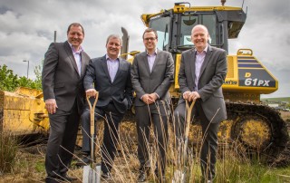 image of four wcctv directors in front of a bulldozer at the site of their new premises